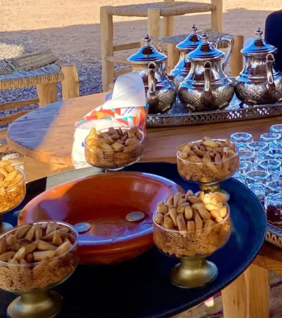 A beautiful Agafay Desert camp dinner setup featuring traditional Moroccan tea, snacks, and an authentic desert ambiance.