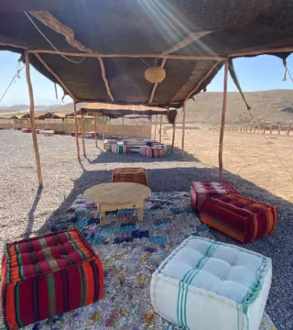Traditional seating area with colorful cushions set up for the Agafay Desert dinner and camel ride, offering stunning desert views.