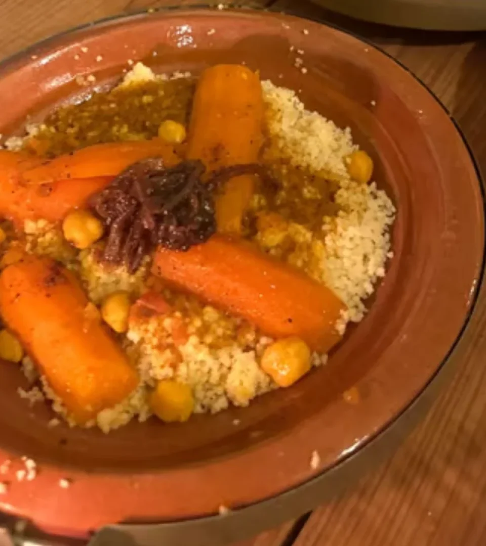 A delicious plate of traditional Moroccan couscous with carrots, chickpeas, and spices, served at Agafay Desert sunset dinner.