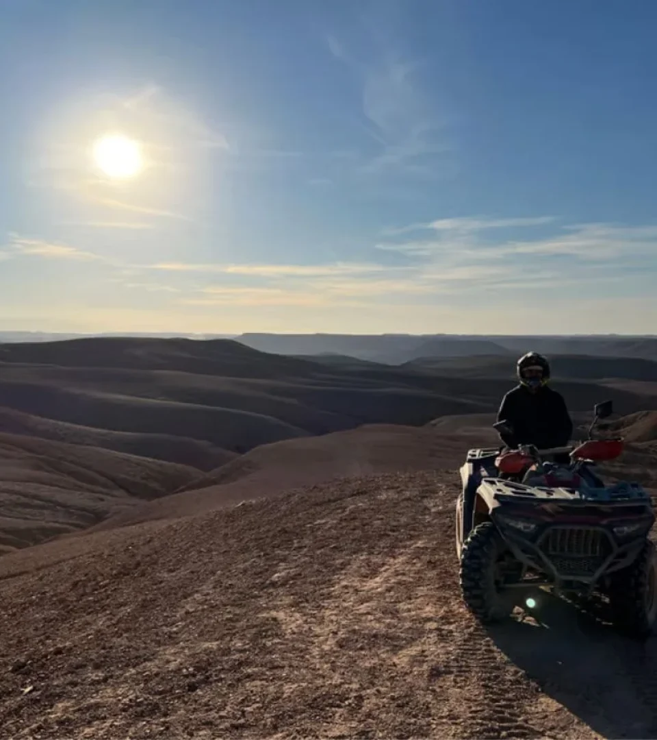 Rider on a quad bike in Agafay Desert, enjoying the stunning landscape near Sun Sky Camp under the bright sun.