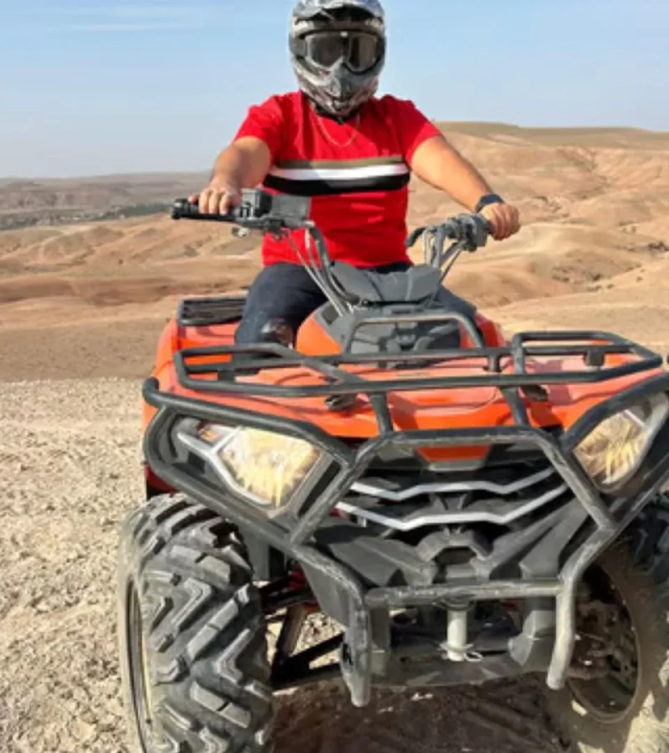Rider on an Agafay Desert quad bike, wearing a helmet and enjoying the thrilling desert landscape under the sun.