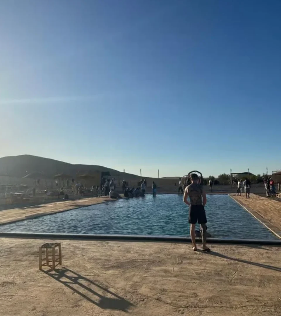 A guest enjoying the pool at the best Morocco desert camp, surrounded by scenic desert landscapes and a relaxing atmosphere.